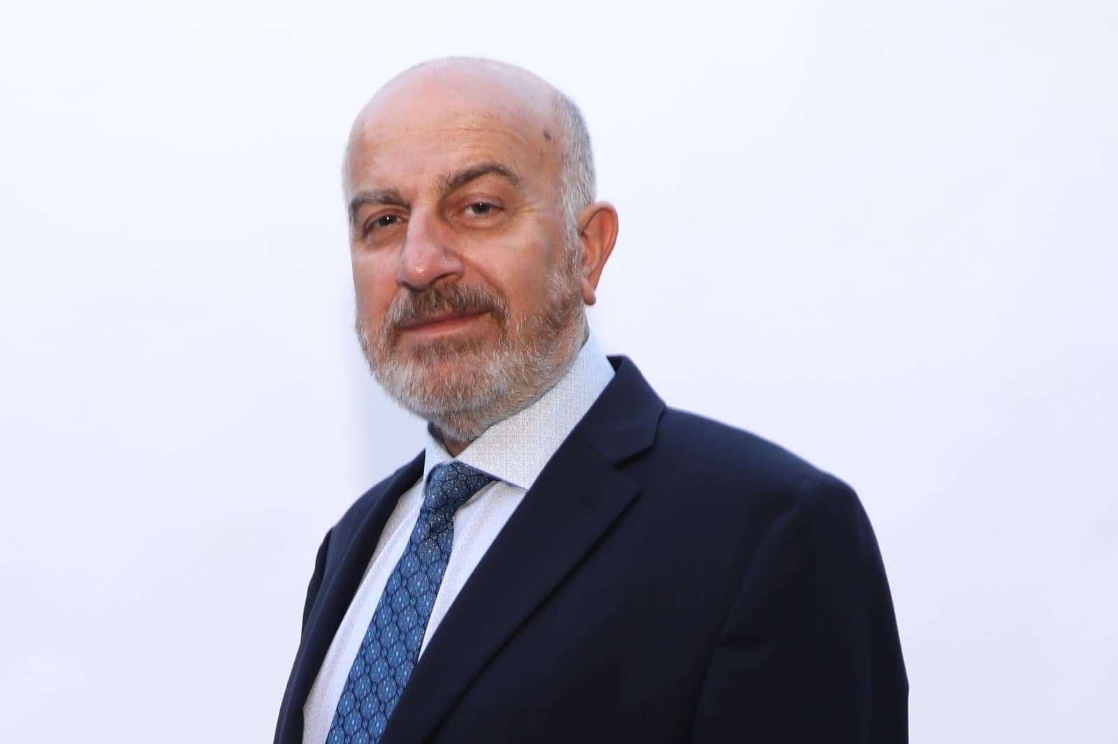 Studio portrait of Serge Khatchadourian in a navy suit