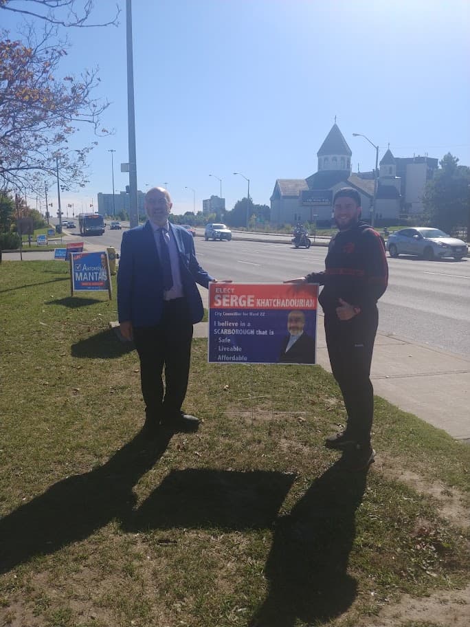 Serge Khatchadourian and a volunteer beside a roadside campaign sign in Scarborough