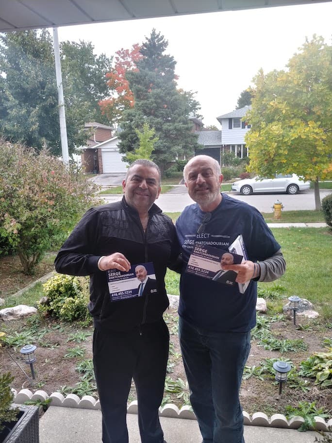 Serge Khatchadourian canvassing with a resident, both holding campaign flyers