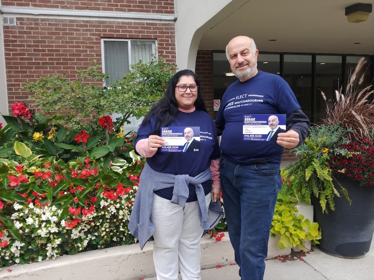 Serge Khatchadourian and a volunteer in campaign shirts outside an apartment building