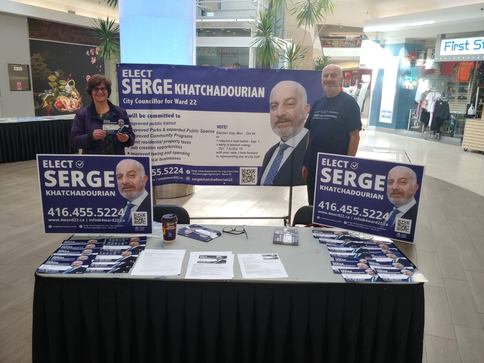 Serge Khatchadourian and a volunteer at a campaign information table in a shopping mall