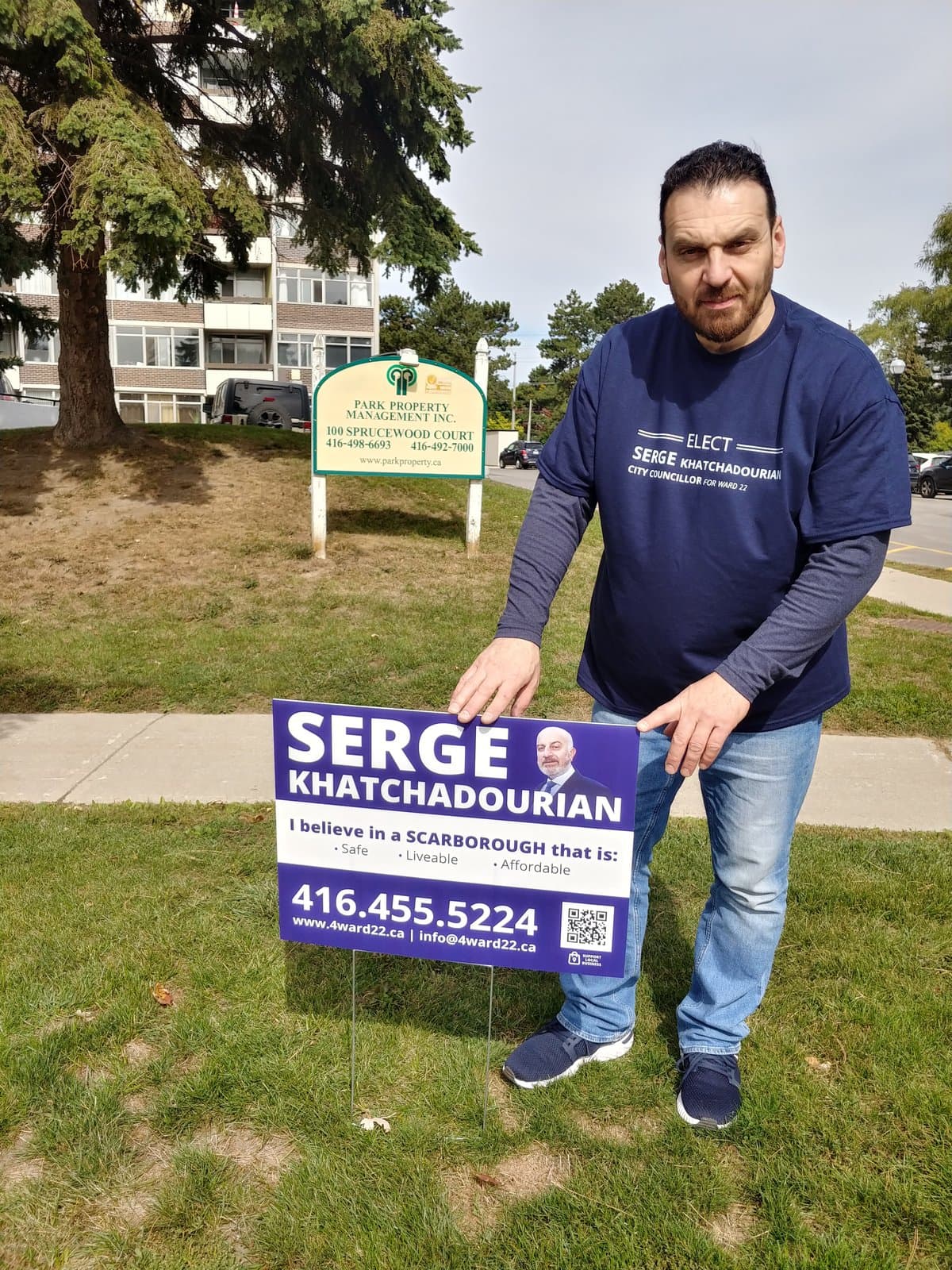 A campaign volunteer installing a lawn sign outside a Scarborough apartment building