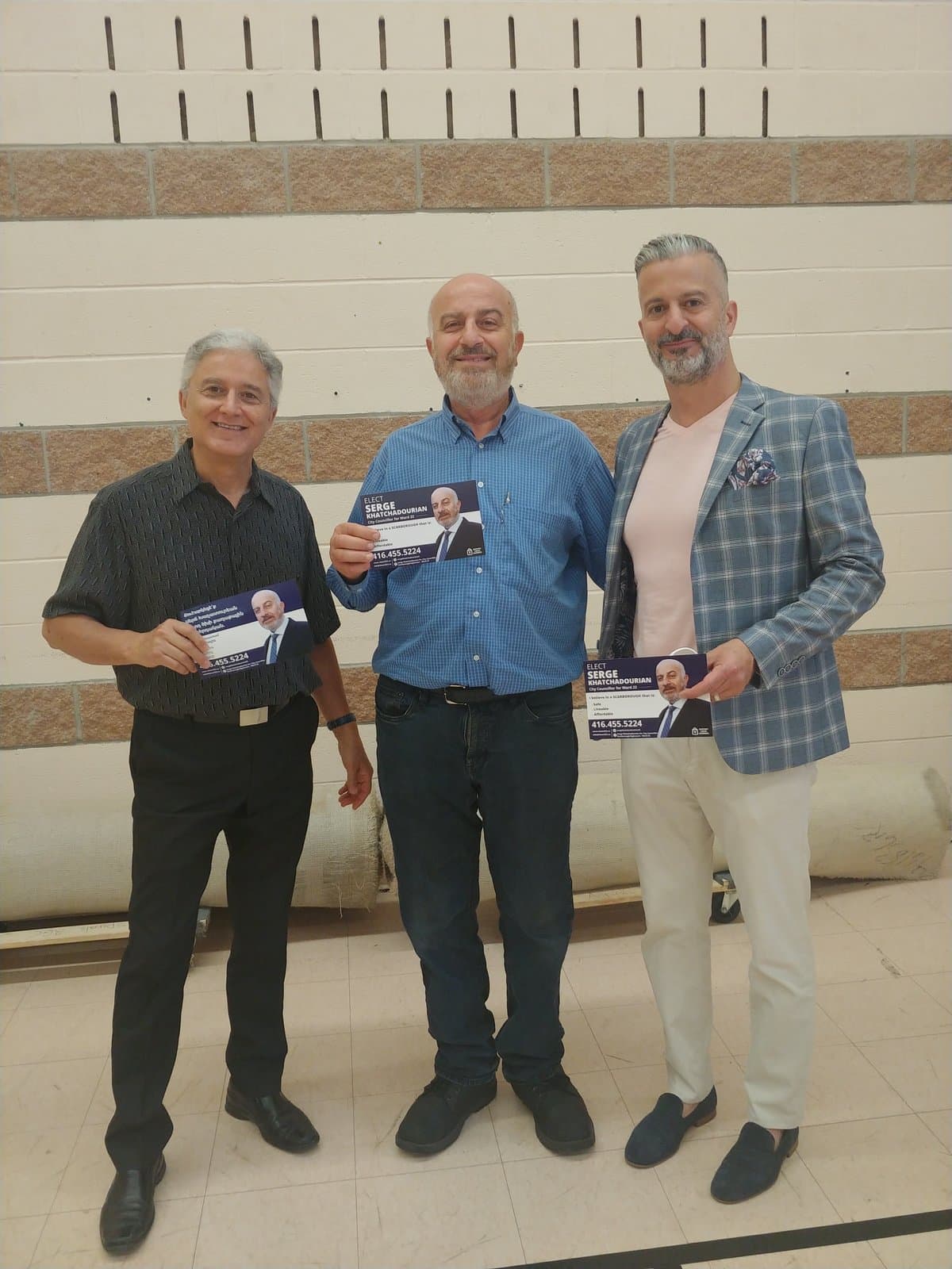 Serge Khatchadourian with supporters holding campaign flyers at a community hall