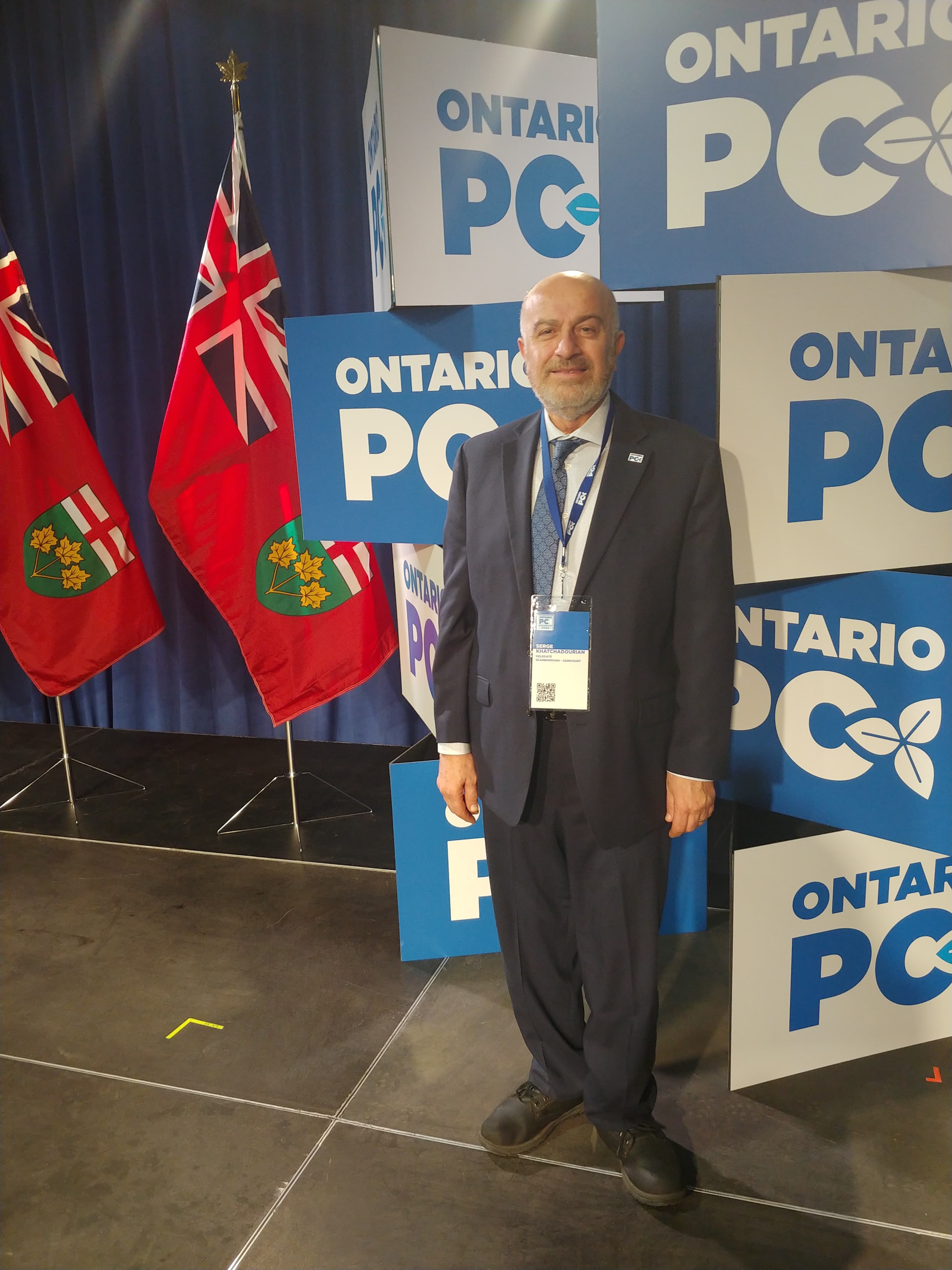 Serge Khatchadourian in front of Ontario PC signs and Ontario flags at a party event